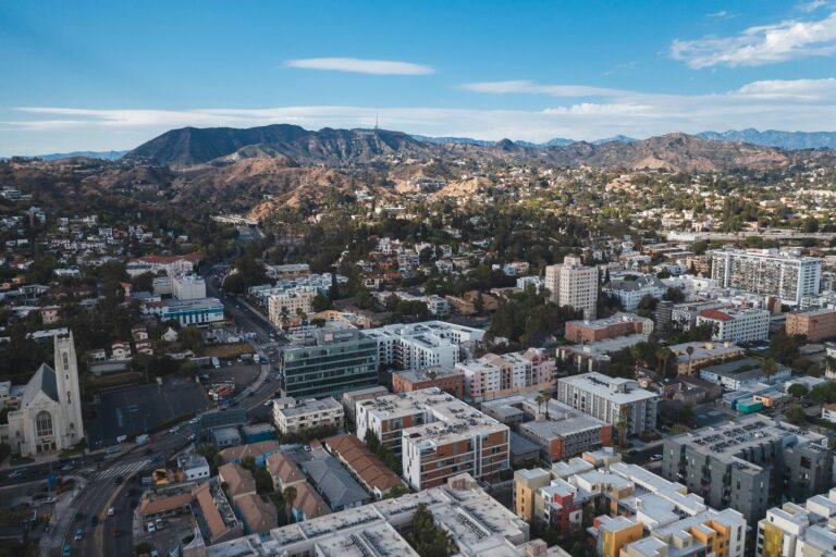 Aerial view of downtown Los Angeles showing buildings, streets, and city skyline under clear skies.